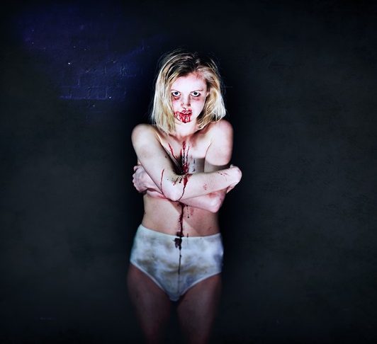 A girl stands in pants with blood on her face