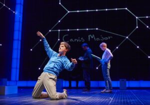 Young man kneels leaning back with Canus Major behind him