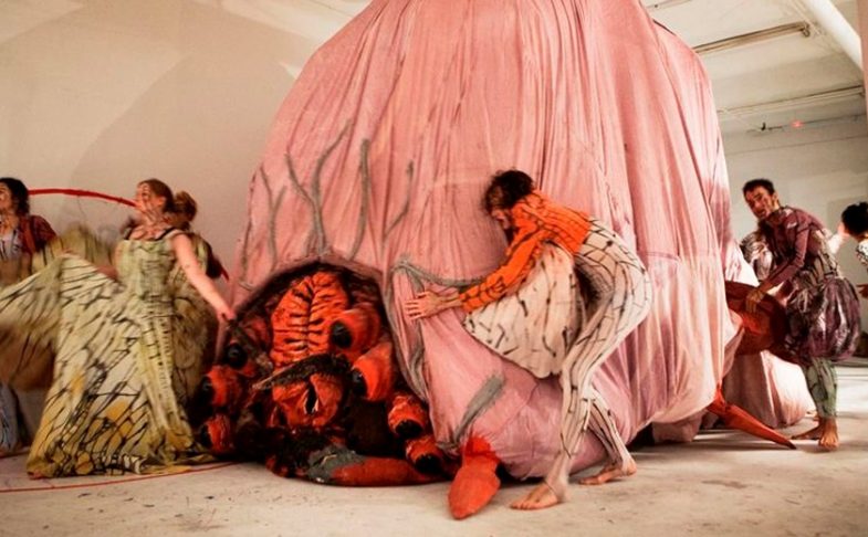 Photo of performers moving a large pink sculpture