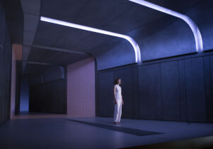 A woman in white in a stark corridor