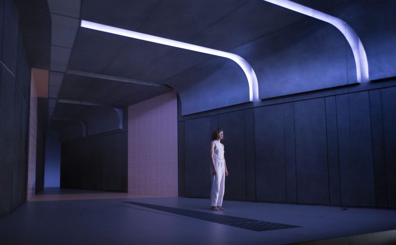 A woman in white in a stark corridor