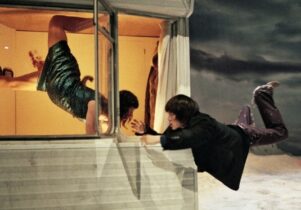 Man and woman levitating at window of caravan