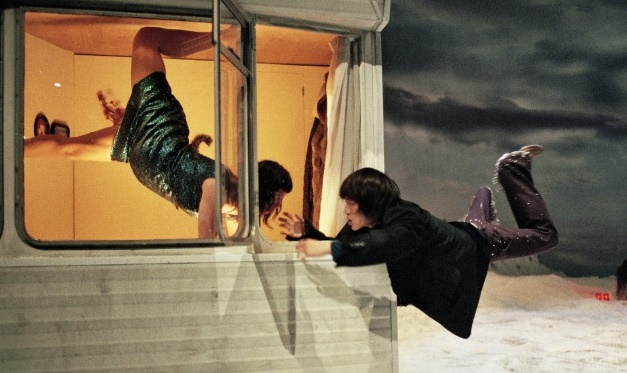 Man and woman levitating at window of caravan