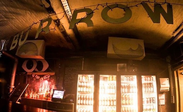 A sign for a Burrow above a bar