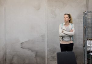 Woman stands against wall