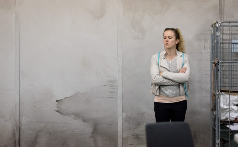 Woman stands against wall