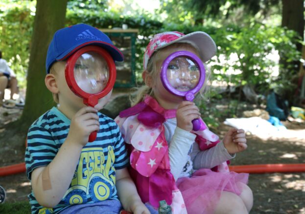 Little explorer at YPS, two children with large magnifying glasses in front of their faces