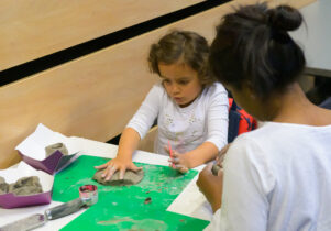child rolling clay at a table in a Family work