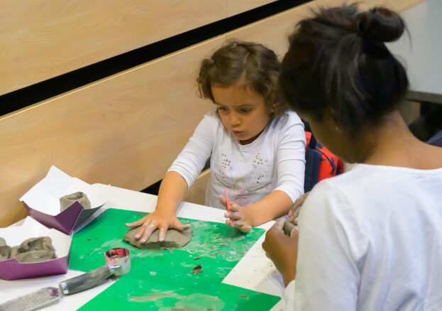 child rolling clay at a table in a Family work