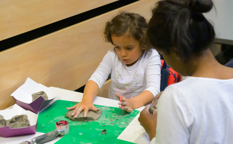 child rolling clay at a table in a Family work