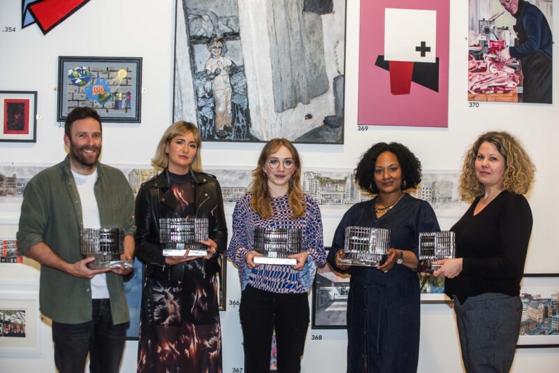 Photo of winners of the Manchester Open 2022 Awards, five people in front of a wall of artwork holidng trophies.