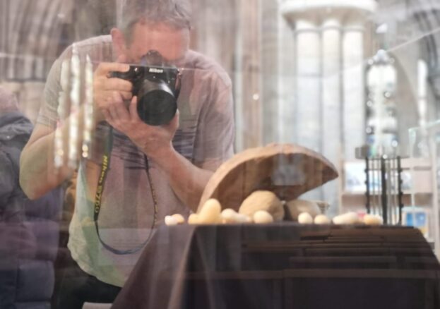 Man taking photo of object in glass case to turn in to 3D models.