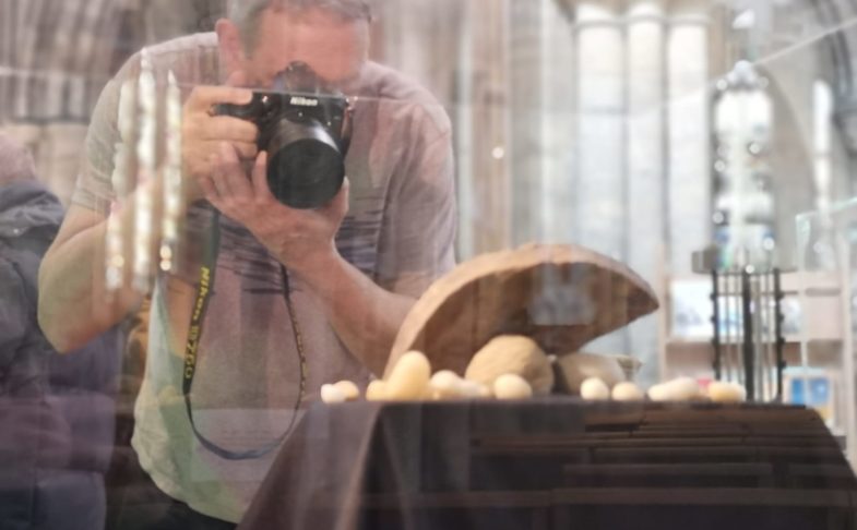 Man taking photo of object in glass case to turn in to 3D models.
