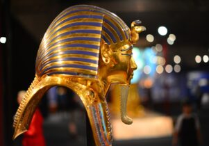A pharoah's mask from Ancient Egypt. Shown in profile the mask is gold and blue with a long gold beard.