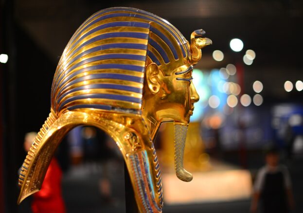 A pharoah's mask from Ancient Egypt. Shown in profile the mask is gold and blue with a long gold beard.