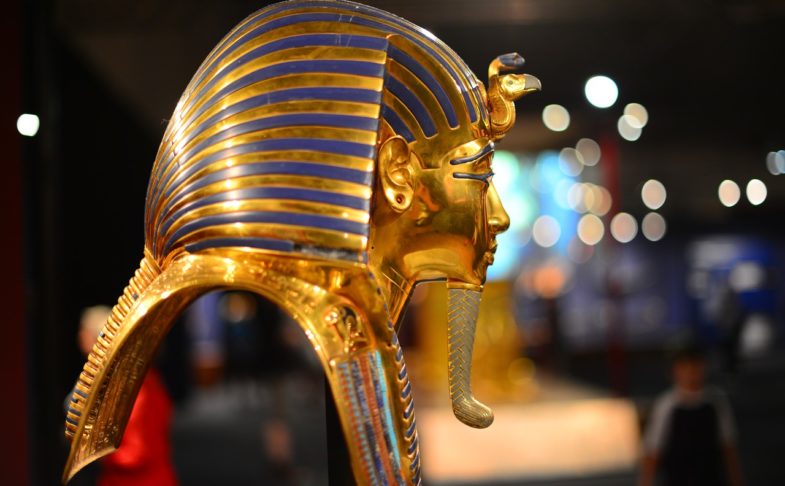 A pharoah's mask from Ancient Egypt. Shown in profile the mask is gold and blue with a long gold beard.