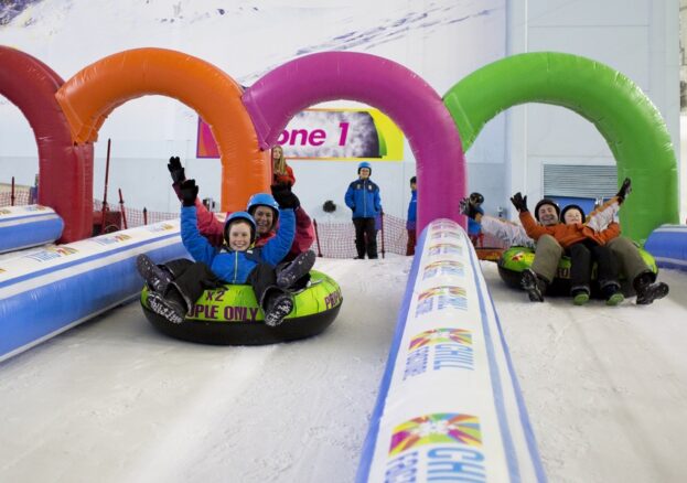 People sliding down the slopes at Chill Factore on an inflatable ring