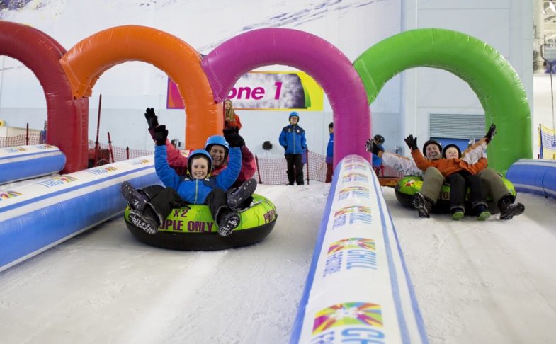 People sliding down the slopes at Chill Factore on an inflatable ring