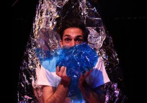 Man holding shiny materials, part of the set for Glisten