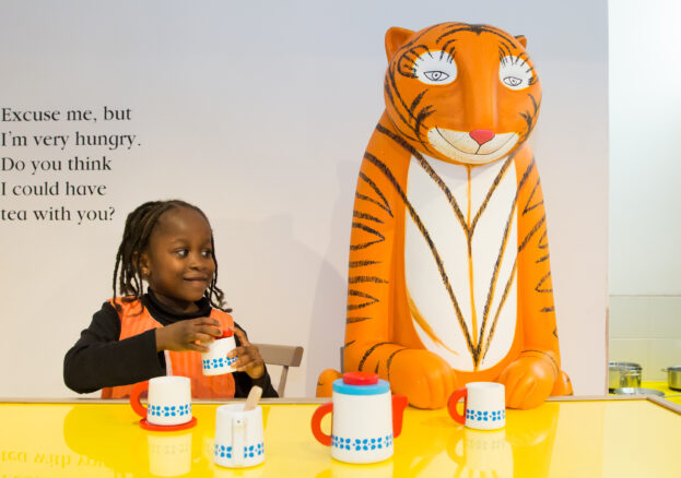 Half term fun - Young girl sat next to the tiger as part of the The Tiger who came to tea and the adventures of mog the forgetful cat exhibition