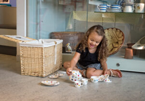 Young girl playing with a tea set at Toddler Tuesdays