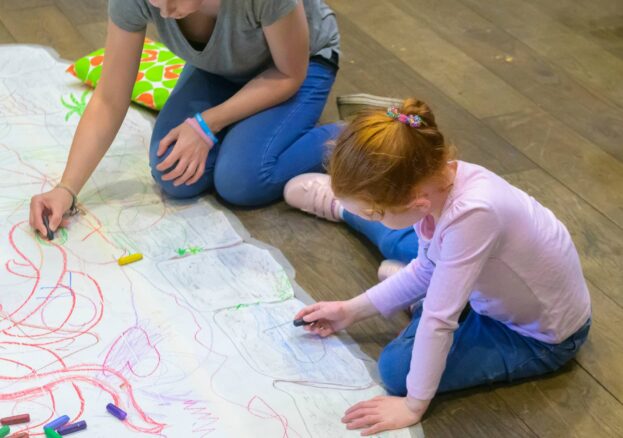 Adult and child drawing on the floor during the Family Weekend event