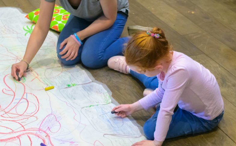 Adult and child drawing on the floor during the Family Weekend event