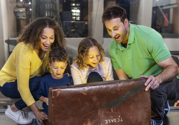 A family looked amazed as they open a large chest in Story Seekers