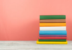 Book stack, hardback colorful books on wooden table and blue background. Back to school. Copy space for text. Education concept