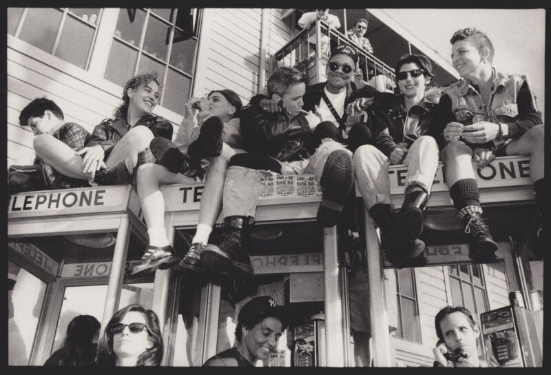 Image of women sitting on top of telephone boxes, photographed by Phyllis Christopher