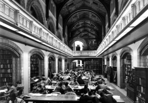 Black and white photograph showing people seated at long tables and studying in the old Reference Library