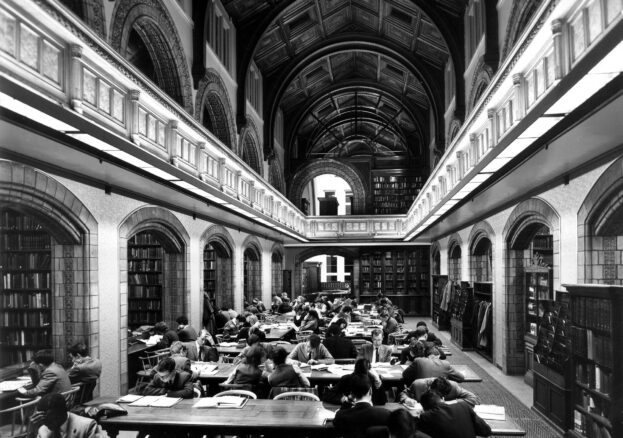 Black and white photograph showing people seated at long tables and studying in the old Reference Library
