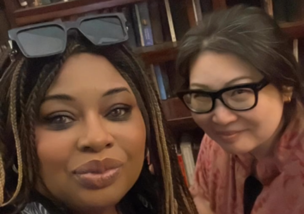 A portrait of 2 women in front of books