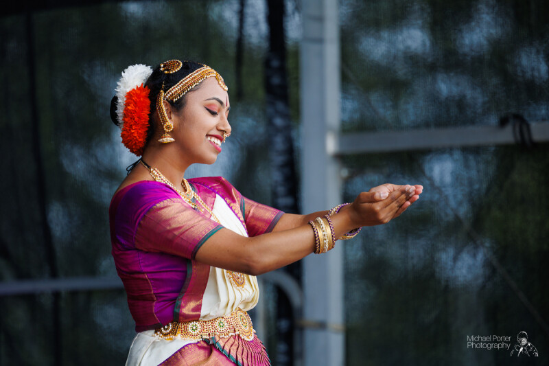 Image of a person in traditional south Asian dress holding their hands out as they dance.