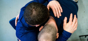 An image captured from overhead of two men embracing. One is seated, and the other is kneeling.