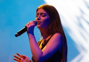 Photo of female artist singing in microphone