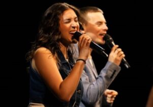 Female and male singing into microphone