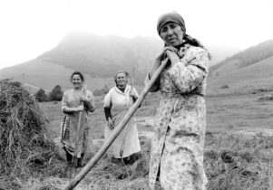 Three woman stand in a field looking at the camera. The photo is black and white.