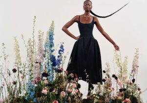 A stylish lady in a black midi dress, among a collection of wildflowers, with her long black hair in a plait