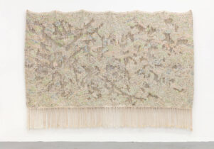 Large beige tapestry with intricate colourful beading hanging on a white wool