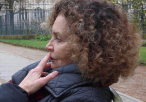 Photo of Beverley with brown curly hair and white skin in a black coat