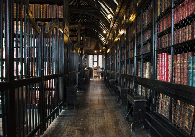A wood panelled corridor with lined with shelves of antique books