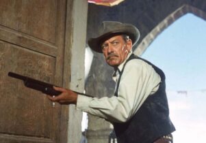 Man in cowboy hat holds a gun