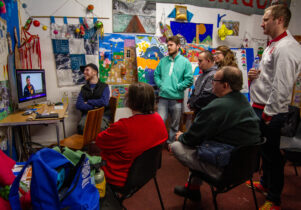 Group of people around a computer screen watch a new documentary from artist