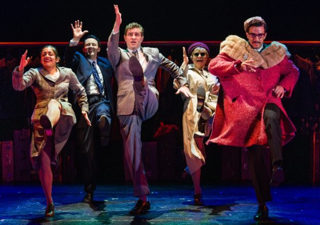 North by Northwest at HOME: Five people stand centre stage with one arm raised in motion, as if all dancing in time.