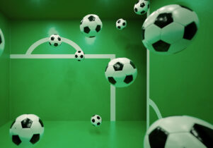 Multiple floating footballs inside a green room with white goalpost markings on the walls. The perspective and reflections create an illusion of depth, making it appear as if the balls are suspended in mid-air.