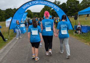 rear shot of three women holding hands about to go under the finish arch