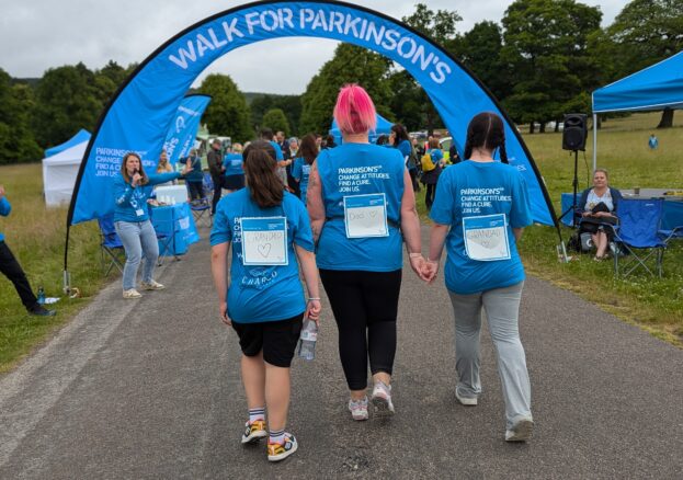 rear shot of three women holding hands about to go under the finish arch