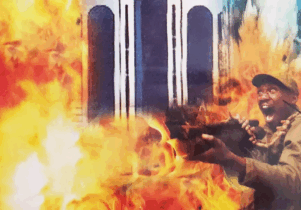 Man dressed in army attire shooting and screaming with fire surrounding him