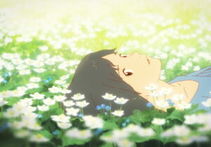 A girl lies down in a field of daisies.